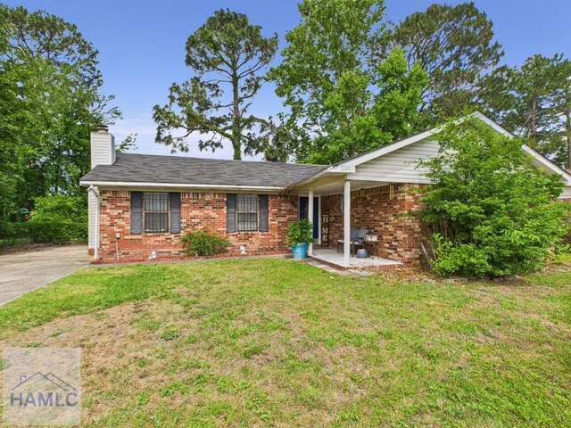 ranch-style home with brick siding, a front yard, and a chimney