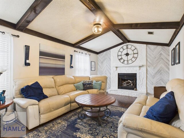 living room featuring wood finished floors, a textured ceiling, and a stone fireplace