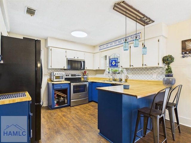 kitchen with appliances with stainless steel finishes, a peninsula, blue cabinets, tasteful backsplash, and white cabinetry