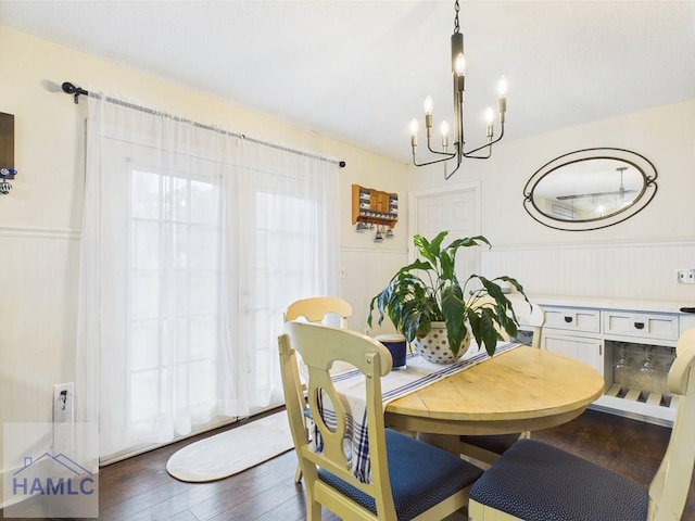 dining space featuring a wainscoted wall, a chandelier, and dark wood-style flooring
