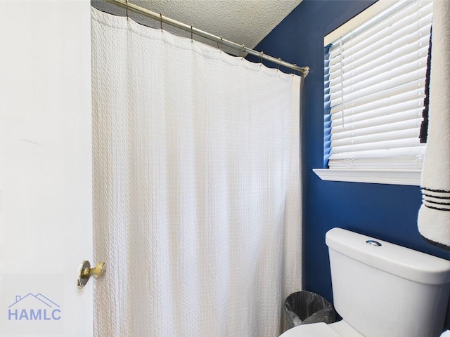 bathroom with toilet and a textured ceiling
