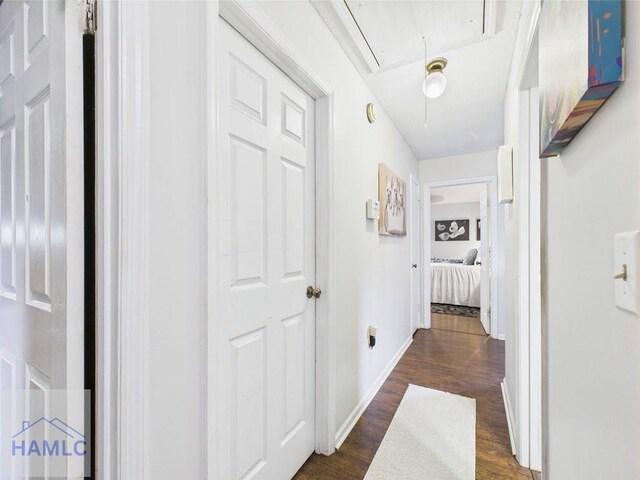 corridor with attic access, dark wood-style flooring, and baseboards