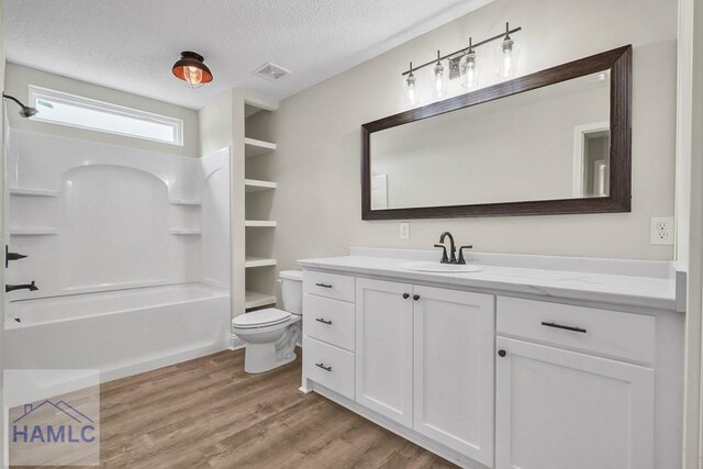 full bathroom featuring vanity, a textured ceiling, wood-type flooring, washtub / shower combination, and toilet