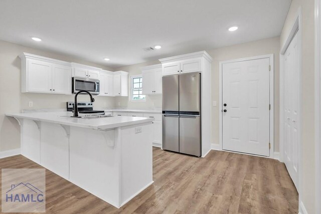 kitchen featuring white cabinetry, kitchen peninsula, appliances with stainless steel finishes, and light hardwood / wood-style flooring