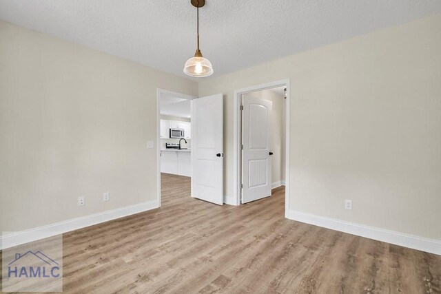 spare room with a textured ceiling and light hardwood / wood-style floors