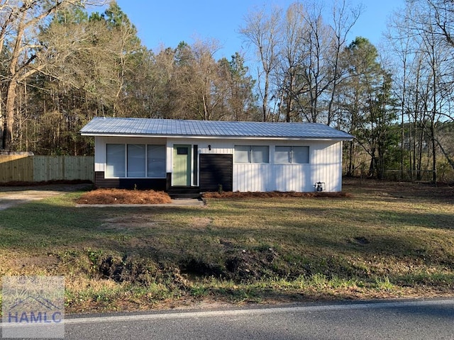 view of front of home with entry steps, metal roof, a front lawn, and fence