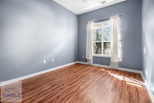 unfurnished room with a ceiling fan, visible vents, baseboards, and wood finished floors