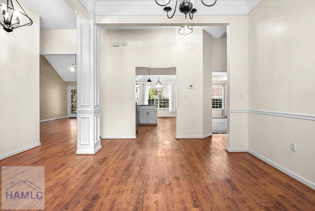 unfurnished dining area with dark wood-style flooring, decorative columns, and baseboards