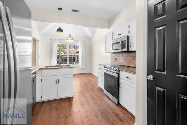 kitchen with pendant lighting, stainless steel appliances, visible vents, white cabinets, and light stone countertops