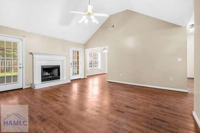 unfurnished living room featuring a tile fireplace, visible vents, baseboards, a ceiling fan, and dark wood finished floors