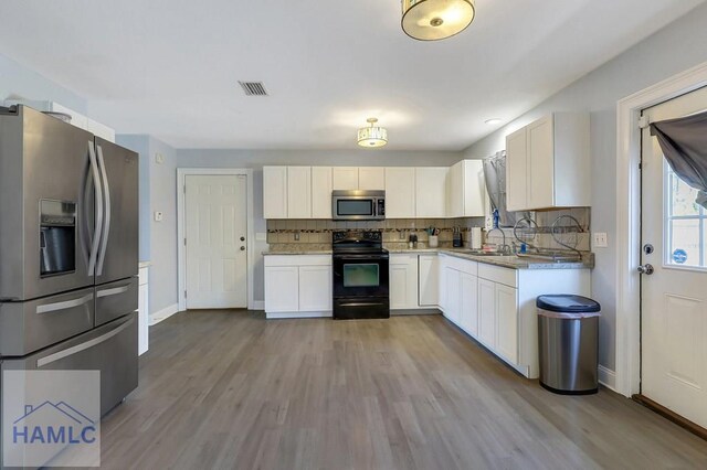 243 Forest St, Ludowici, GA 31316 - kitchen featuring white cabinets, appliances with stainless steel finishes, decorative backsplash, wood finished floors, and visible vents