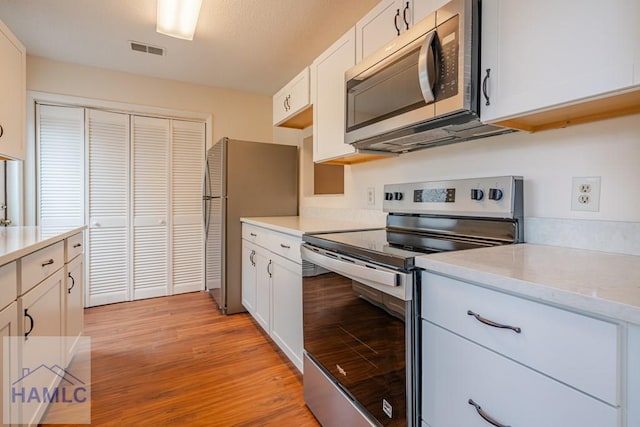 727S Main St Unit 121, Hinesville, GA 31313 - kitchen featuring appliances with stainless steel finishes, light countertops, light wood-style floors, and white cabinetry