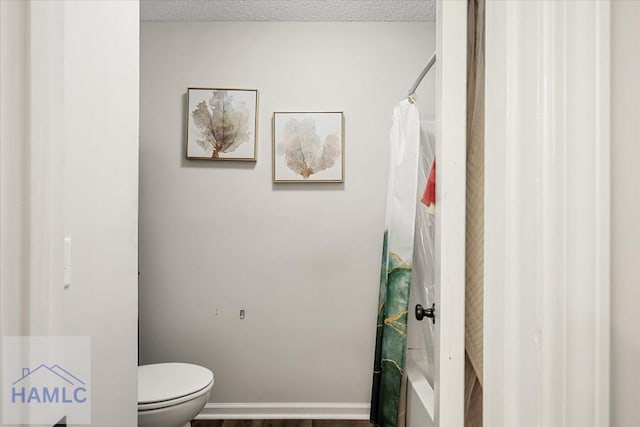 bathroom with shower / bath combo, a textured ceiling, and toilet