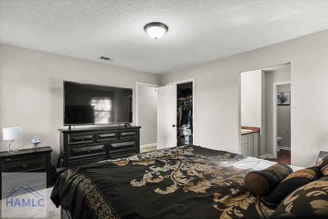 bedroom featuring a textured ceiling, connected bathroom, and a closet