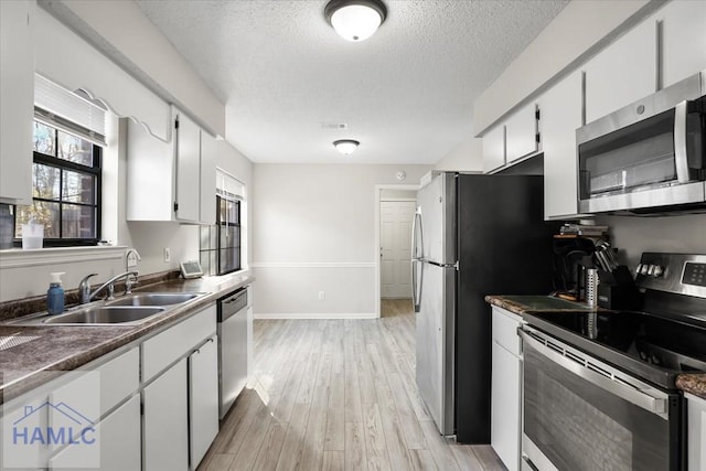 kitchen with sink, white cabinets, stainless steel appliances, and light wood-type flooring