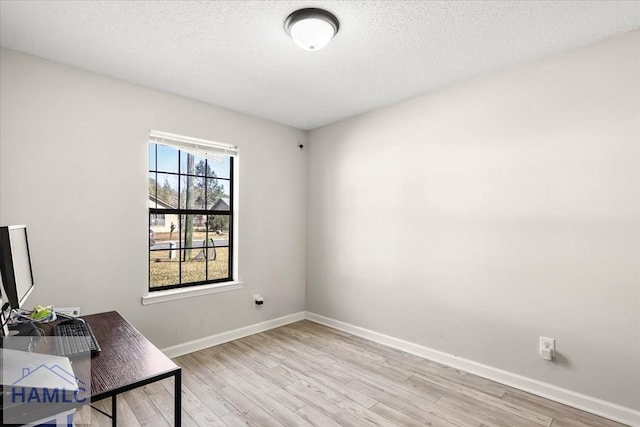 home office with light hardwood / wood-style floors and a textured ceiling