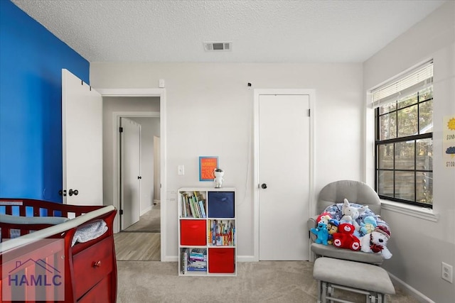 bedroom featuring light colored carpet and a textured ceiling