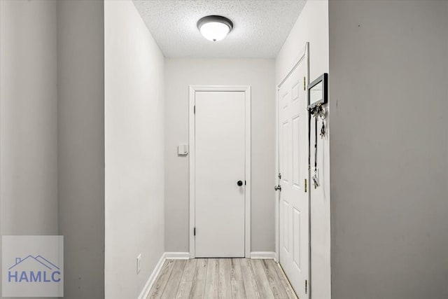 corridor featuring a textured ceiling and light hardwood / wood-style floors