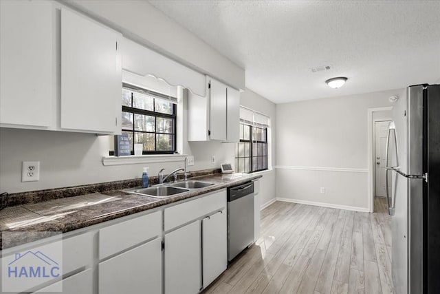 kitchen with white cabinetry, sink, stainless steel appliances, light hardwood / wood-style flooring, and a textured ceiling