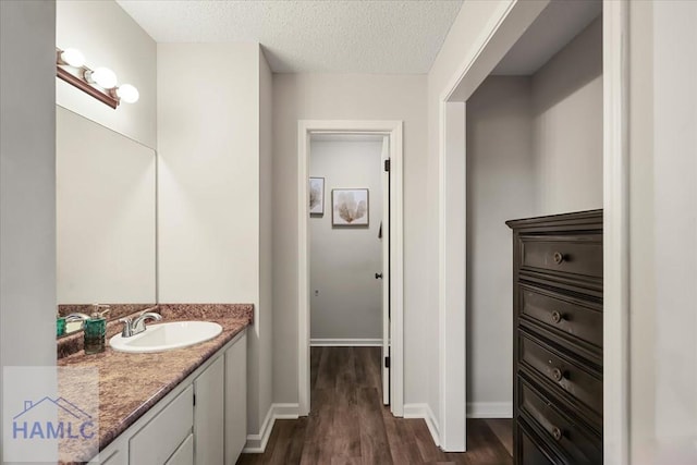 bathroom with hardwood / wood-style floors, vanity, and a textured ceiling