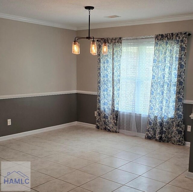 spare room featuring light tile patterned floors, crown molding, baseboards, and visible vents