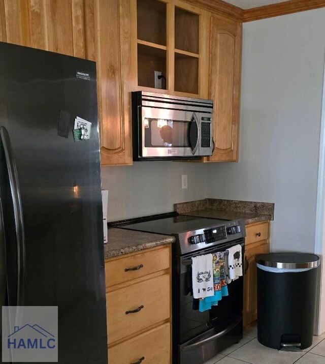 kitchen with dark stone counters, light tile patterned floors, and black appliances