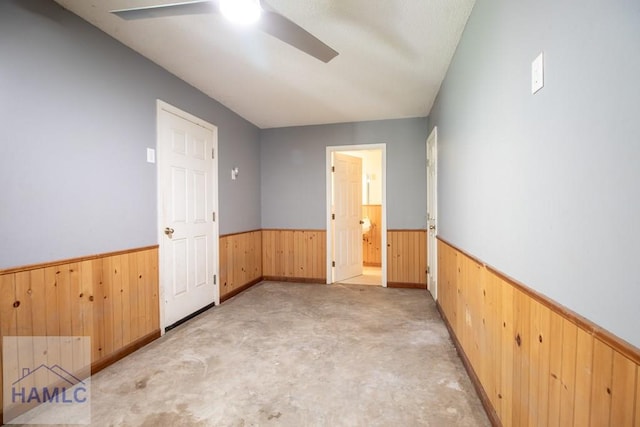 spare room with ceiling fan and wood walls