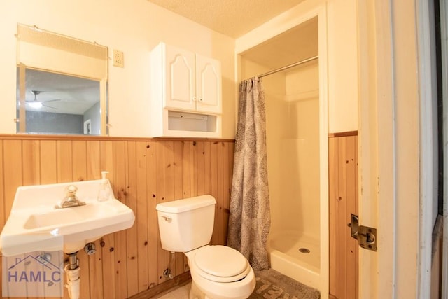 bathroom featuring toilet, walk in shower, wooden walls, and ceiling fan