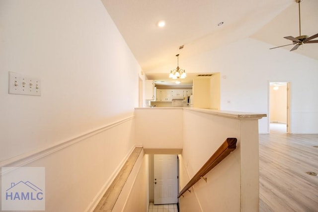 stairway featuring ceiling fan with notable chandelier, wood-type flooring, and high vaulted ceiling