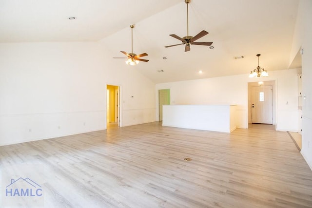 empty room featuring ceiling fan with notable chandelier, light hardwood / wood-style floors, and high vaulted ceiling