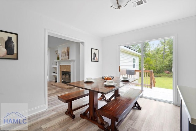 550 Brogdon Rd, Guyton, GA 31312 - dining area with crown molding, light wood-type flooring, a tiled fireplace, and baseboards