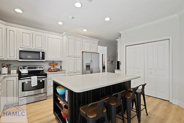 645 Littlefield St, Jesup, GA 31546 - kitchen with appliances with stainless steel finishes, ornamental molding, light countertops, a kitchen island, and a kitchen bar