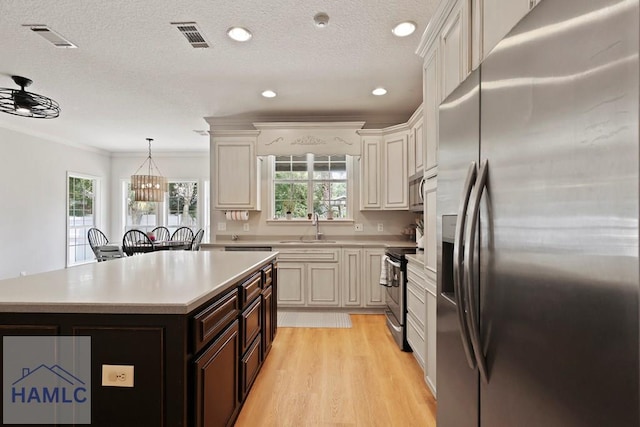 645 Littlefield St, Jesup, GA 31546 - kitchen with appliances with stainless steel finishes, light countertops, dark brown cabinets, a kitchen island, and a textured ceiling