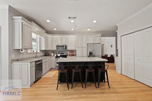645 Littlefield St, Jesup, GA 31546 - kitchen featuring appliances with stainless steel finishes, crown molding, light countertops, light wood-style flooring, and a kitchen breakfast bar