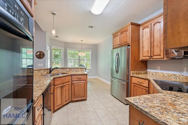 190 Sandpiper Rd, Midway, GA 31320 - kitchen featuring black appliances, a sink, brown cabinets, light stone counters, and decorative light fixtures