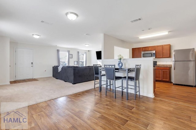 kitchen with light wood-type flooring, a kitchen breakfast bar, and appliances with stainless steel finishes