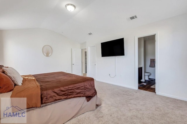 carpeted bedroom with lofted ceiling and ensuite bath