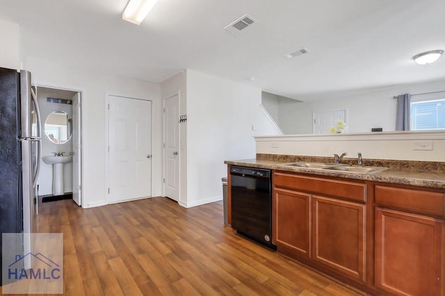 kitchen with dark hardwood / wood-style flooring, sink, stainless steel fridge, and black dishwasher