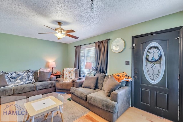 living room with ceiling fan, wood-type flooring, and a textured ceiling