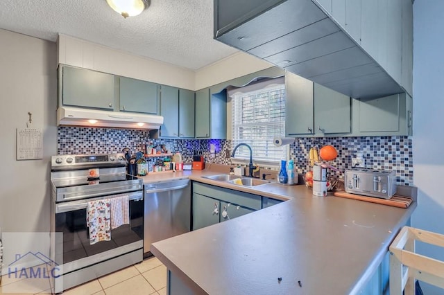 kitchen featuring sink, decorative backsplash, light tile patterned floors, a textured ceiling, and appliances with stainless steel finishes