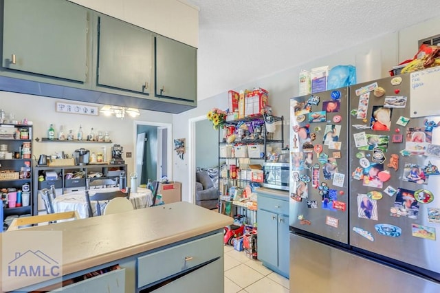 kitchen featuring light tile patterned floors, a textured ceiling, and stainless steel appliances