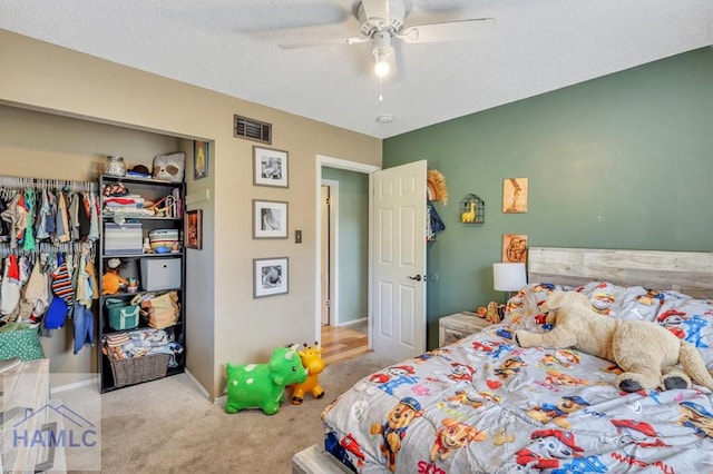 bedroom with ceiling fan, light carpet, and a textured ceiling