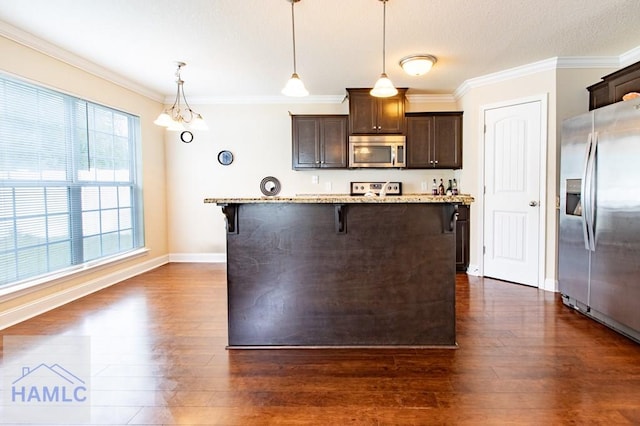 kitchen featuring dark wood-type flooring, hanging light fixtures, a breakfast bar area, light stone countertops, and stainless steel appliances