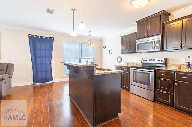 kitchen featuring a kitchen bar, dark hardwood / wood-style flooring, stainless steel appliances, pendant lighting, and a center island