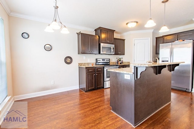 kitchen featuring a breakfast bar, pendant lighting, stainless steel appliances, and dark wood-type flooring