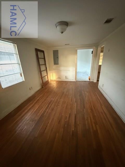 empty room featuring visible vents, baseboards, wood finished floors, and ornamental molding