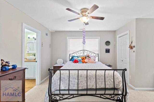 bedroom featuring connected bathroom, ceiling fan, sink, light colored carpet, and a closet