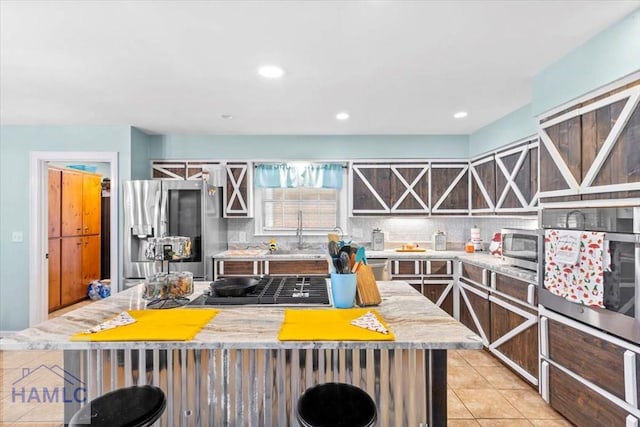 kitchen featuring light tile patterned flooring, sink, tasteful backsplash, a kitchen island, and stainless steel appliances