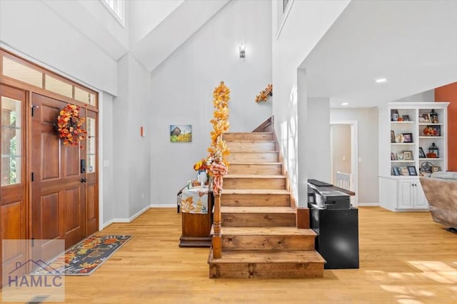 entrance foyer with light hardwood / wood-style flooring and high vaulted ceiling