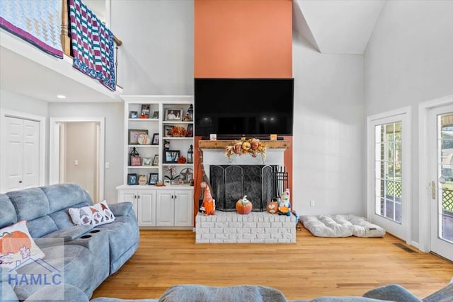 living room featuring a fireplace, light hardwood / wood-style flooring, and high vaulted ceiling